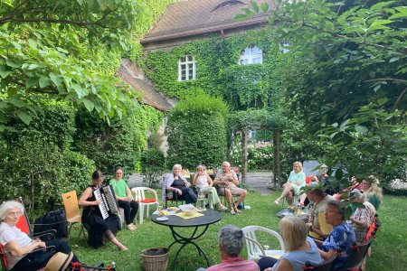 Menschen sitzen im Gartenund singen gemeinsam